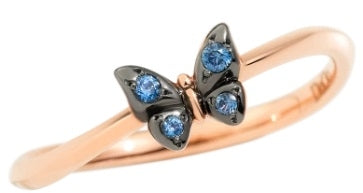 Rose gold butterfly ring on finger, black metal accents and blue gemstone details visible